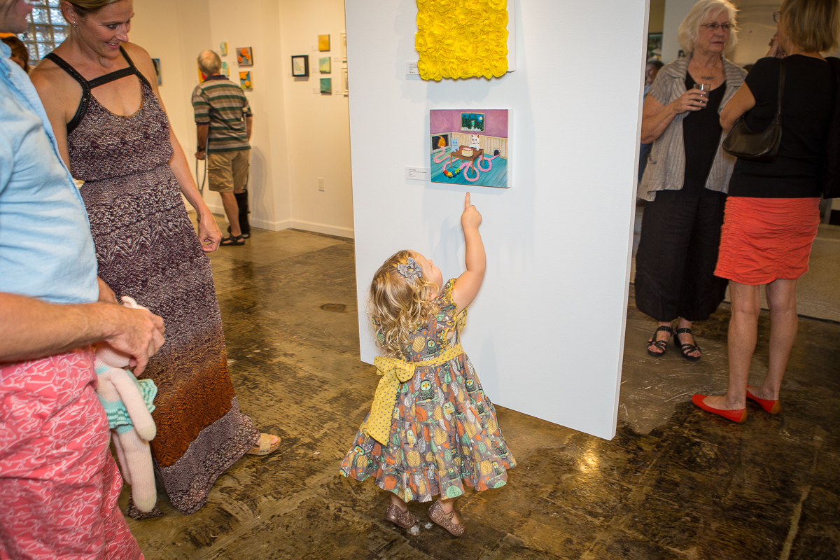 Young blonde girl pointing at an artwork